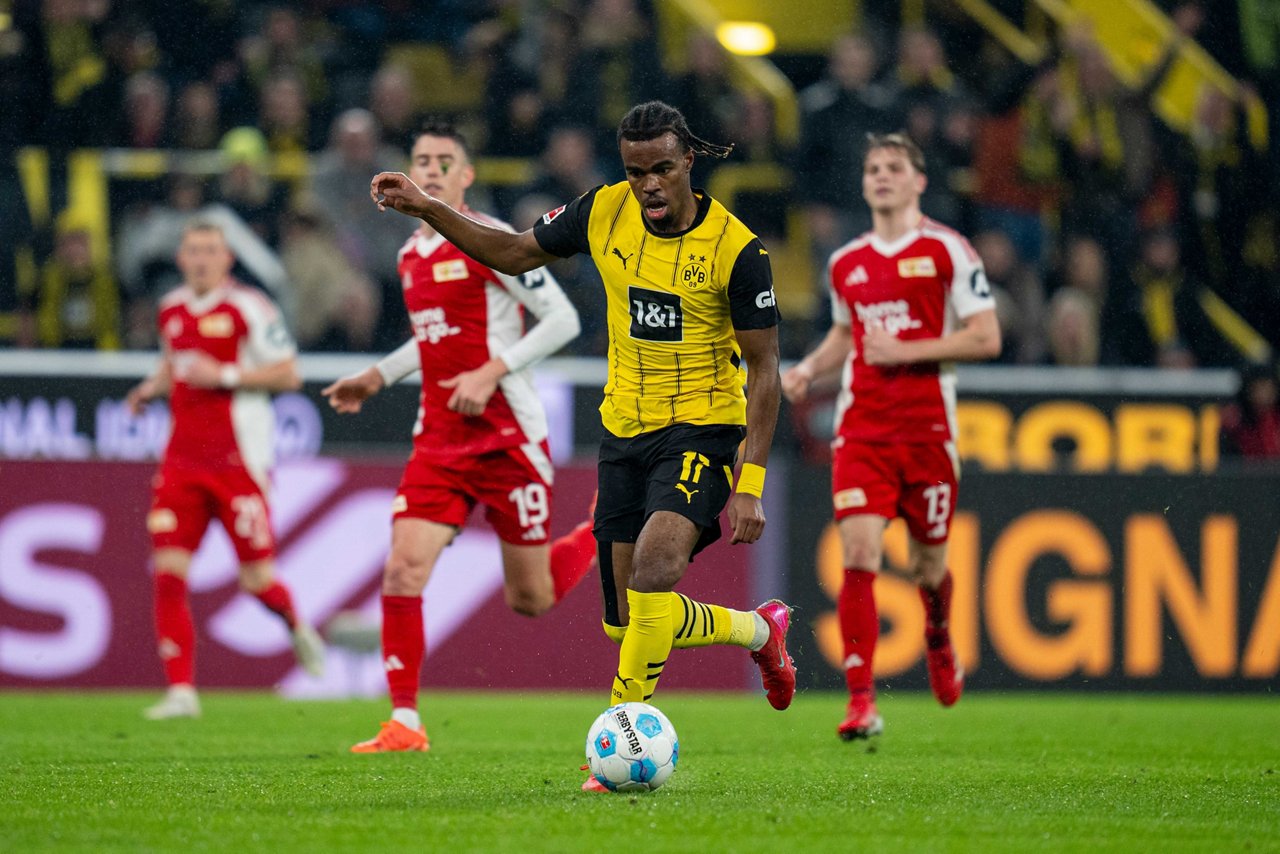 Carney Chukwuemeka hat in der Begegnung zwischen Borussia Dortmund und Union Berlin im Februar 2025 den Ball am Fuß. Im Hintergrund sieht man drei Spieler aus Berlin.