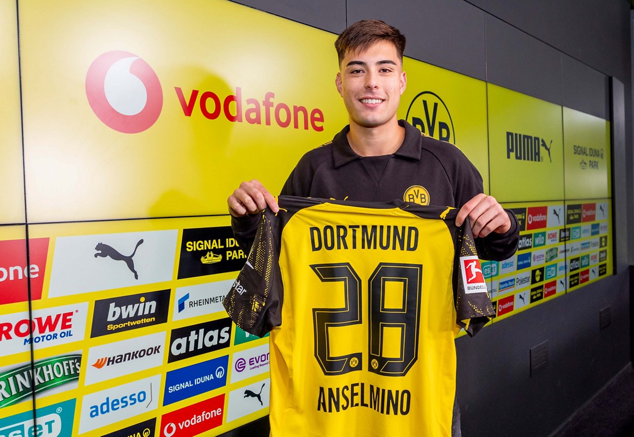 Aaron Anselmino hält ein BVB-Trikot mit seiner Rückennummer 28.