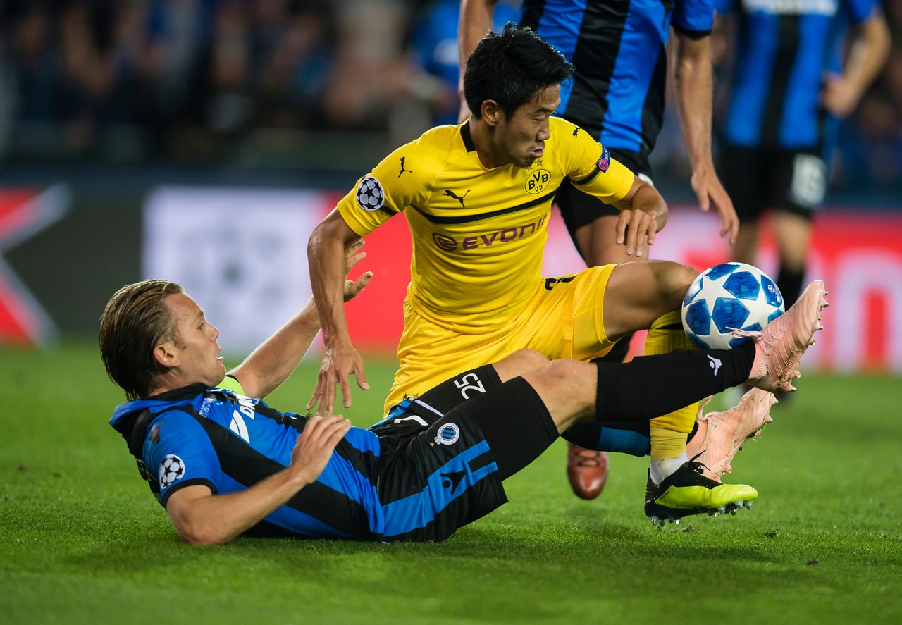 Shinji Kagawa auf einem Knie im Zweikampf mit einem Brügge-Spieler.