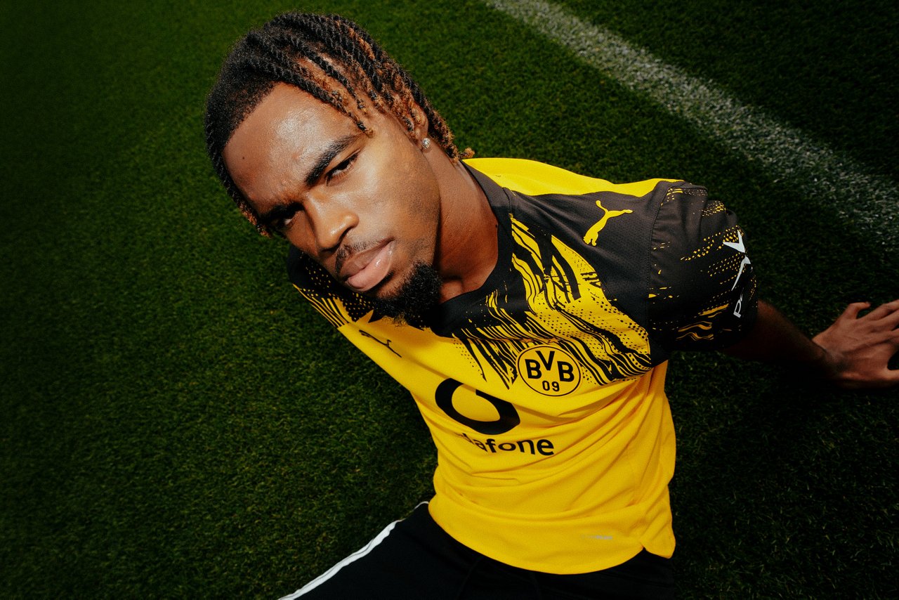 Carney Chukwuemeka sitzt in BVB-Trikot vor einer Vodafone-Bande.