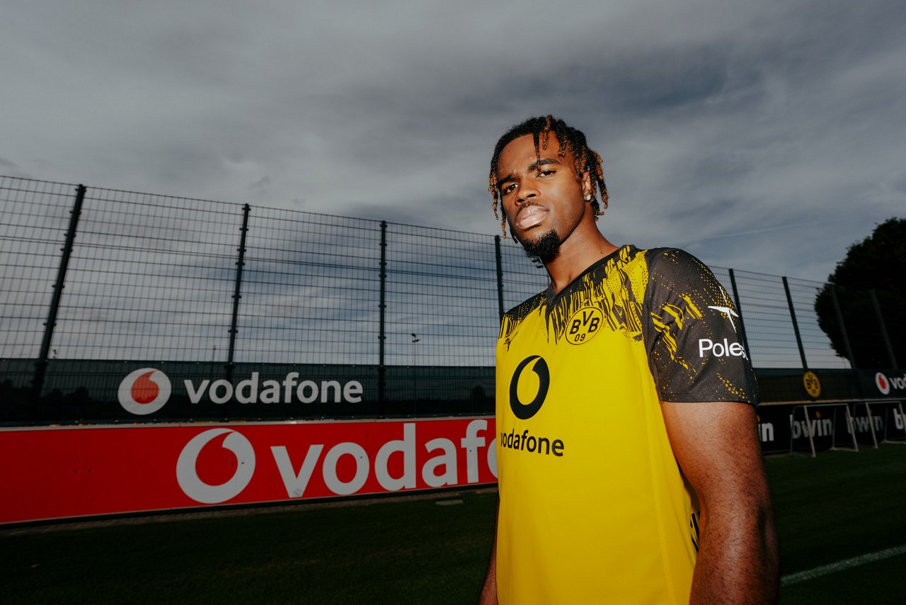Carney Chukwuemeka steht in BVB-Trikot vor einer Vodafone-Bande.