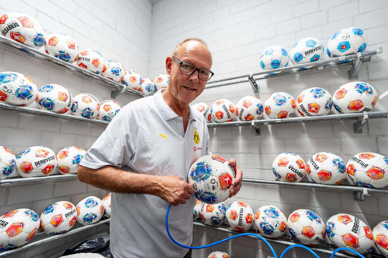 Frank Gräfen pumpt einen Ball auf. Hinter ihm in den Regalen liegen weitere Bälle.