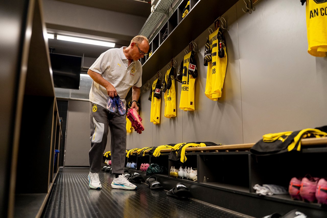 Frank Gräfen legt in der Mannschaftskabine Schuhe an die Plätze der Spieler.