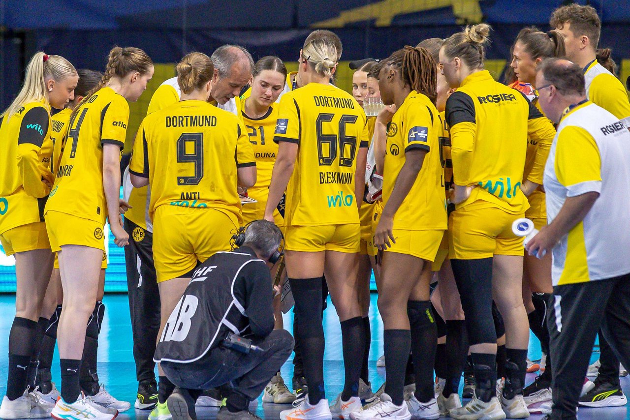Die BVB-Handballerinnen bilden während einer Auszeit einen Kreis. Trainer Henk Groener spricht.