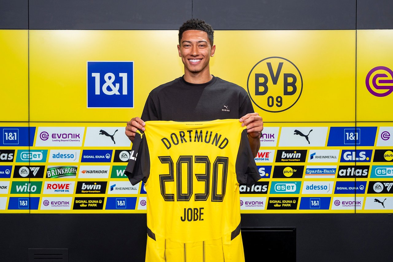 Jobe Bellingham hält Trikot, dass vertragslaufzeit bis 2030 zeigt, in die Luft.