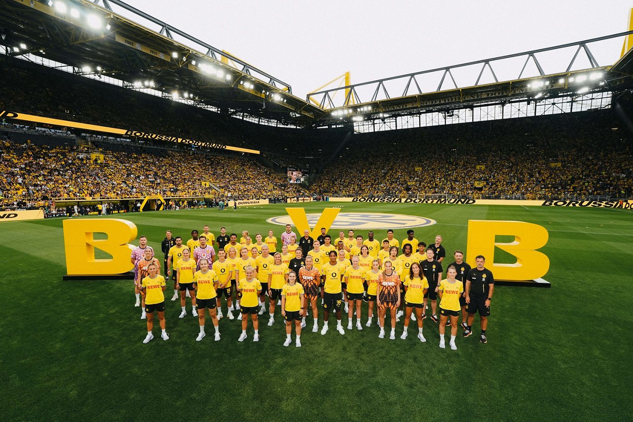 Die Mannschaften der BVB-Profis und BVB-Frauen auf dem Rasen.