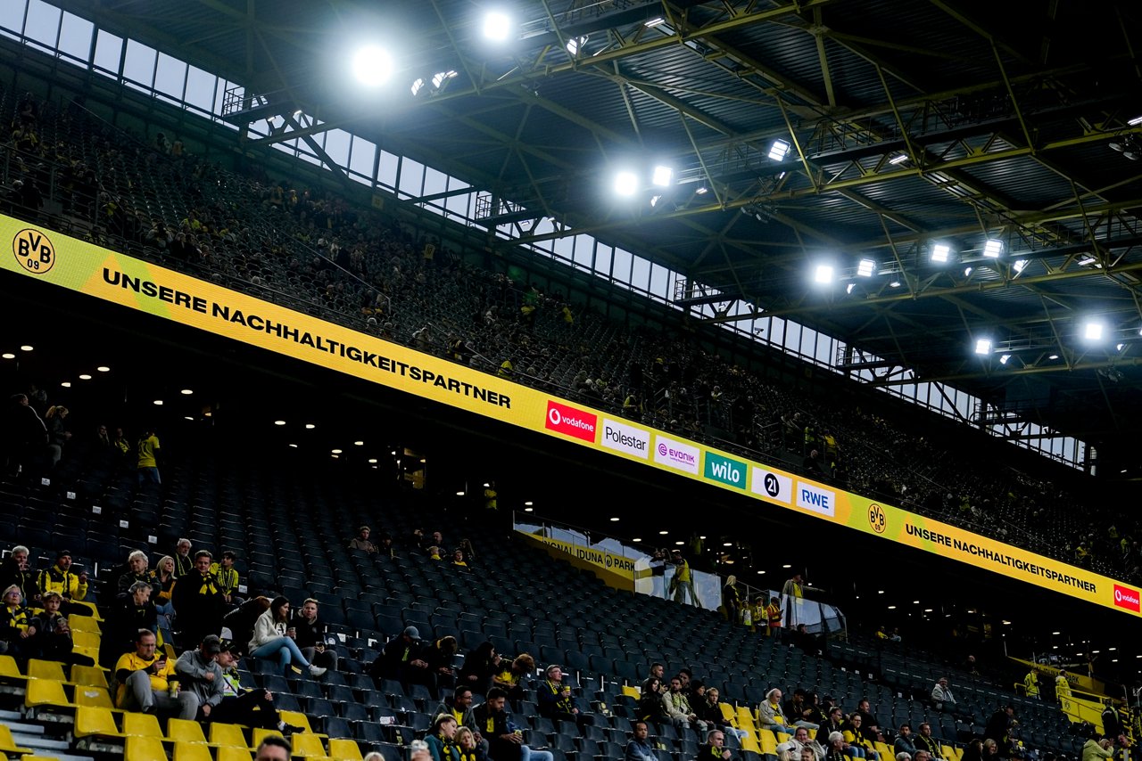 Die Logos der Nachhaltigkeitspartner Vodafone, Polestar, Evonik, Wilo, 21 und RWE werden auf einer Bande im Oberrang des Stadions angezeigt.