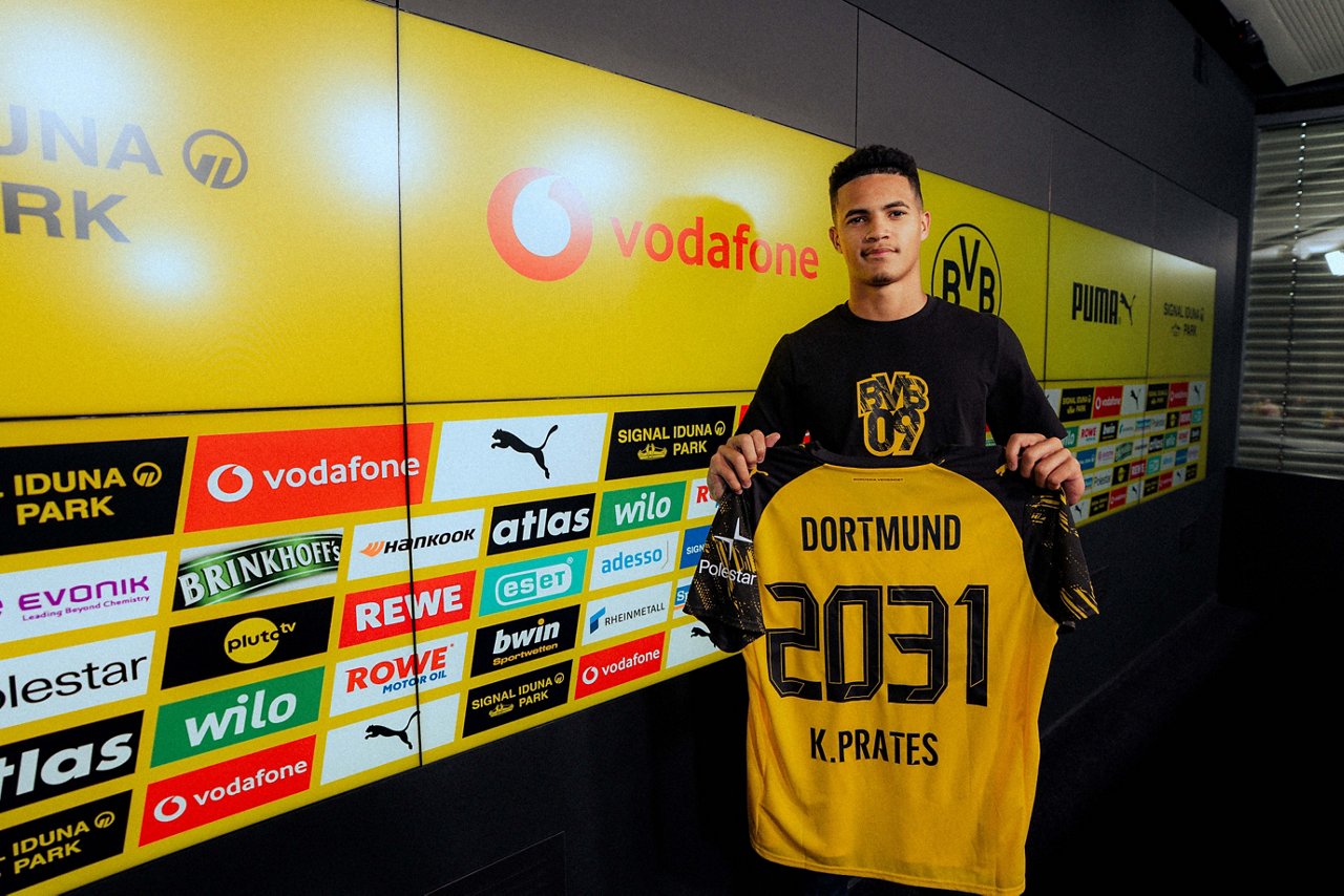 Kaua Prates hält ein BVB-Trikot mit der Aufschrift 2031 hoch.