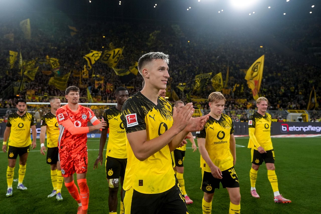 Nico Schlotterbeck klatscht in die Hände. Im Hintergrund sind andere BVB-Spieler zu sehen.