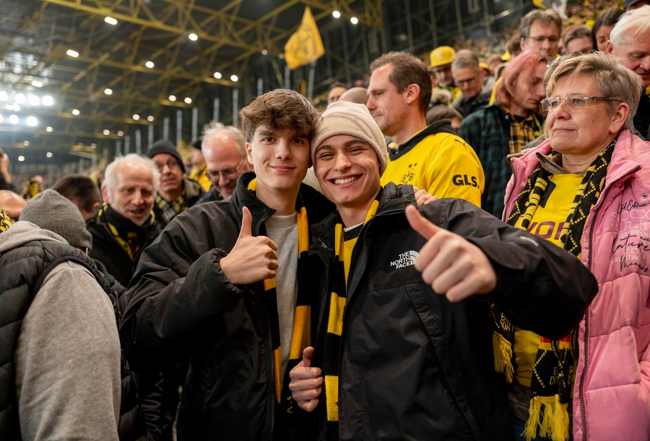 2 jugendliche männliche Fans stehen auf der Südtribühne des Signal Iduna Parks und strecken ihren Daumen nach oben