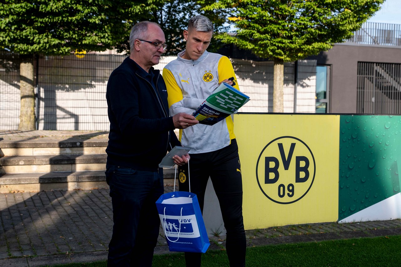Nico Schlotterbeck und ein VDV-Vertreter beugen sich über eine Zeitschrift.