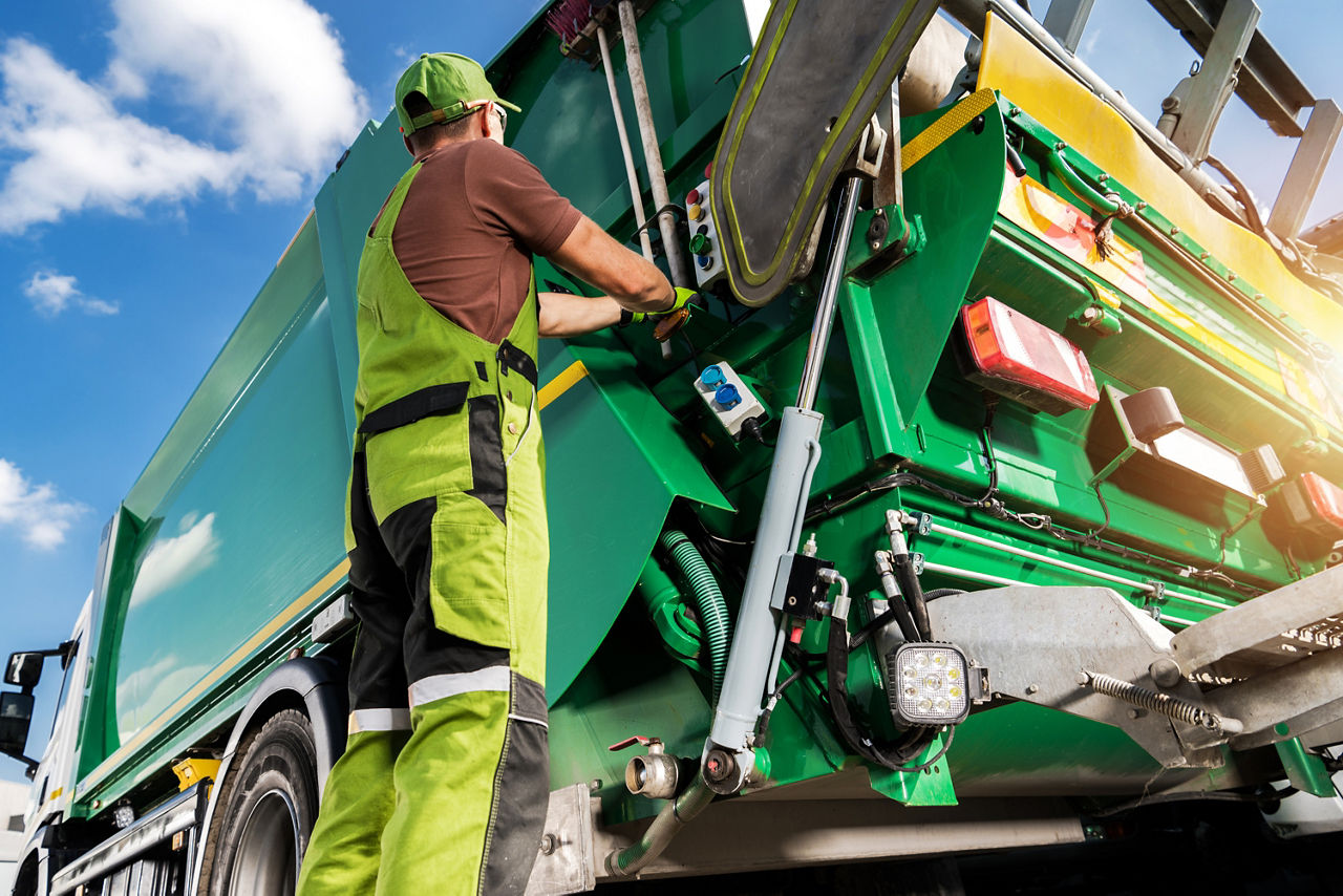 Modern Garbage Truck and Caucasian Waste Collector Worker. Waste Sorting and Management Theme.