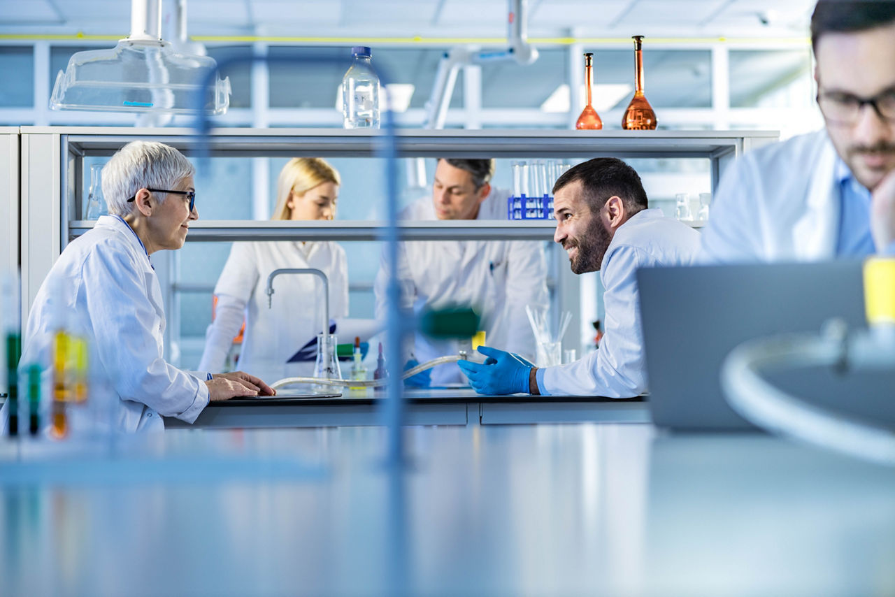 Group of medical experts working together in laboratory. Focus is on two of them communicating. Copy space.