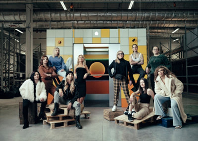10 female apprentices on crates in front of an elevator in a warehouse