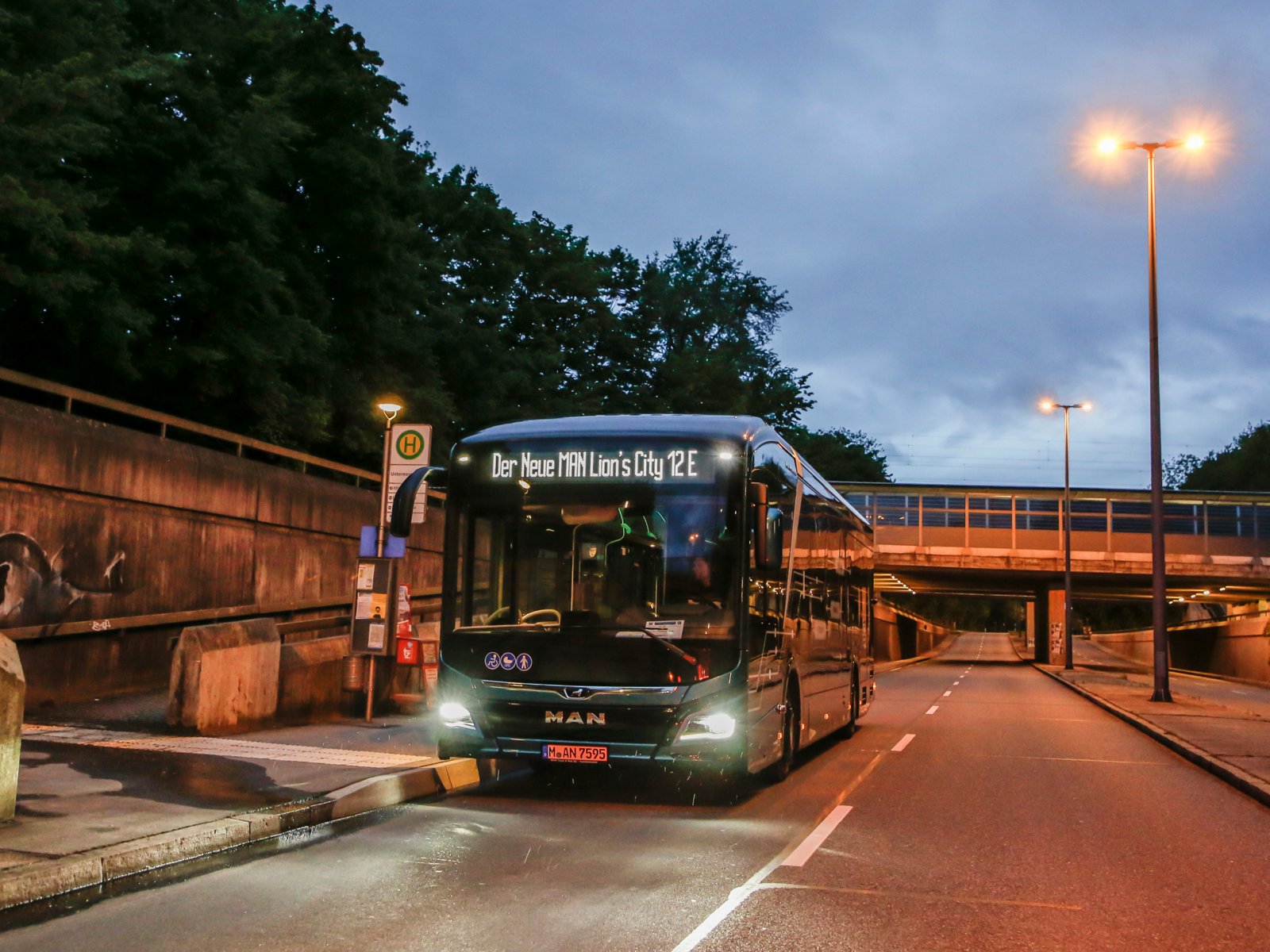 A MAN Lion's City E at a bus top at night. 