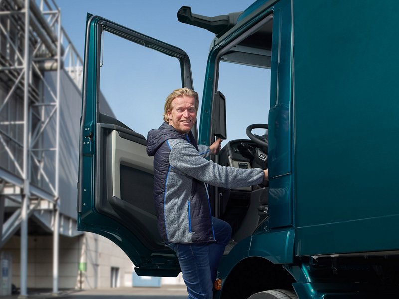 Chauffeur gebruikt de trap om in een MAN-vrachtwagen te stappen.