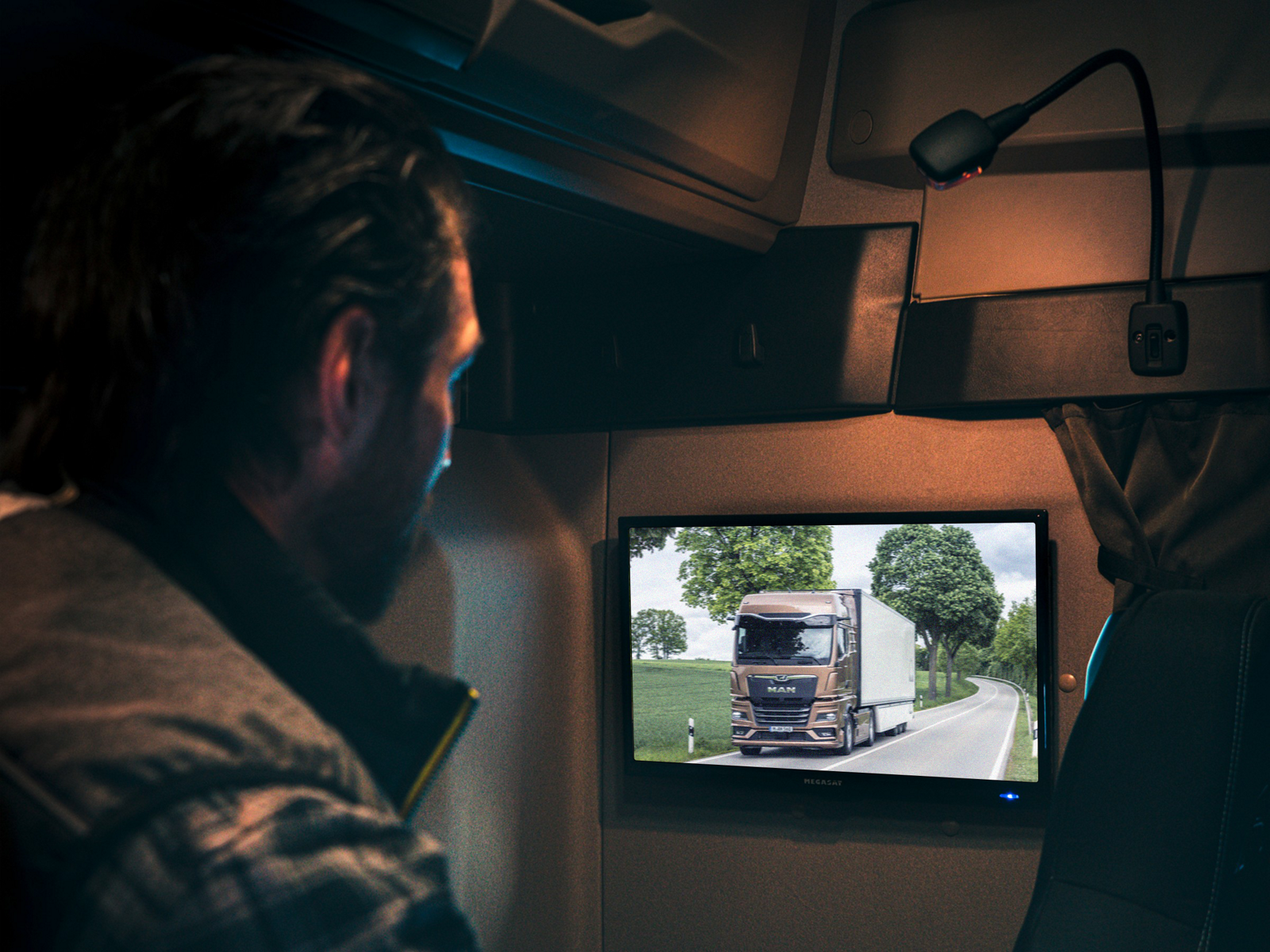 Řidič sleduje televizi ve svém nákladním automobilu MAN.