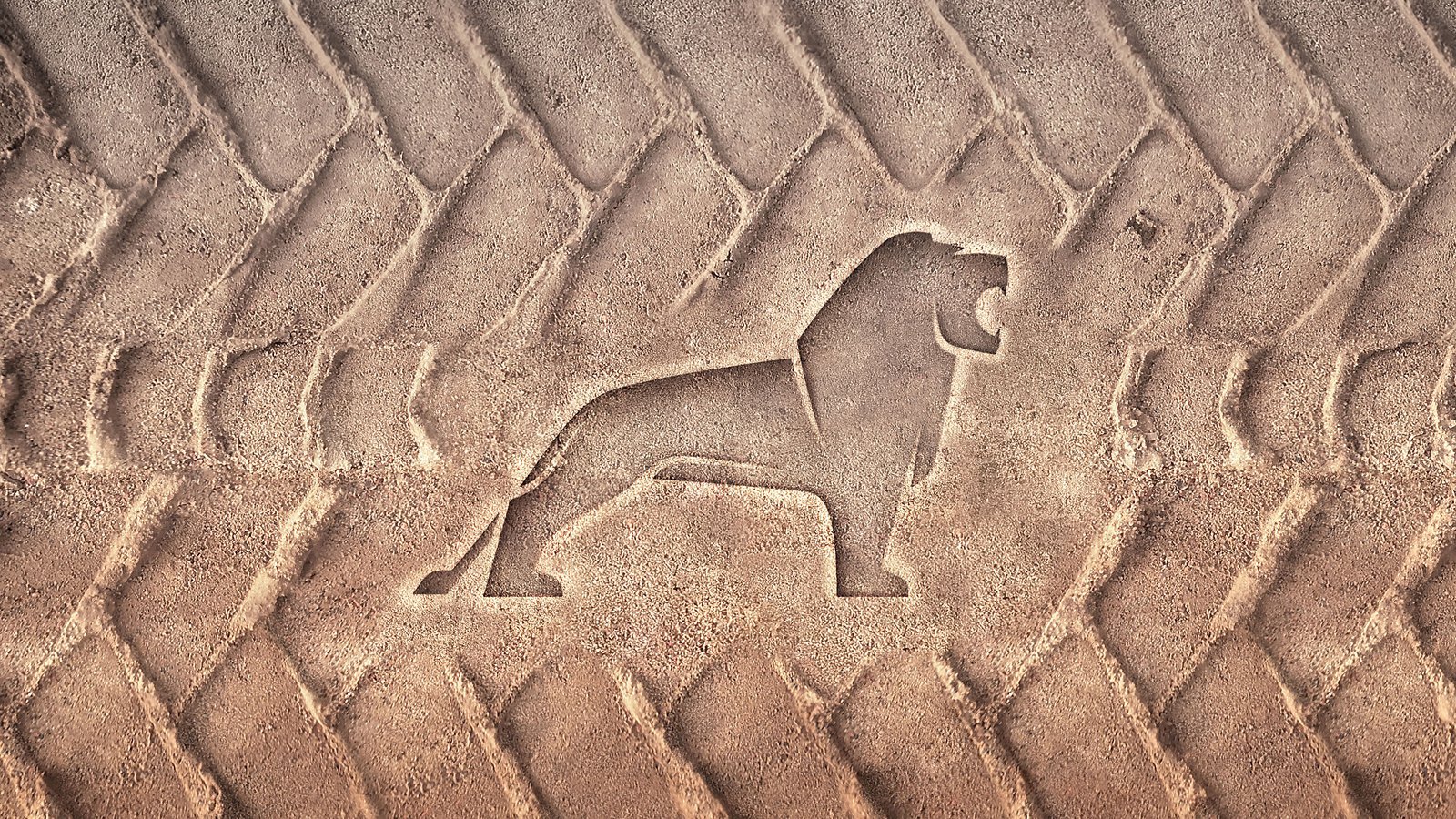 Silhouette de lion imprimée dans le sable entourée de traces de pneus tout-terrain