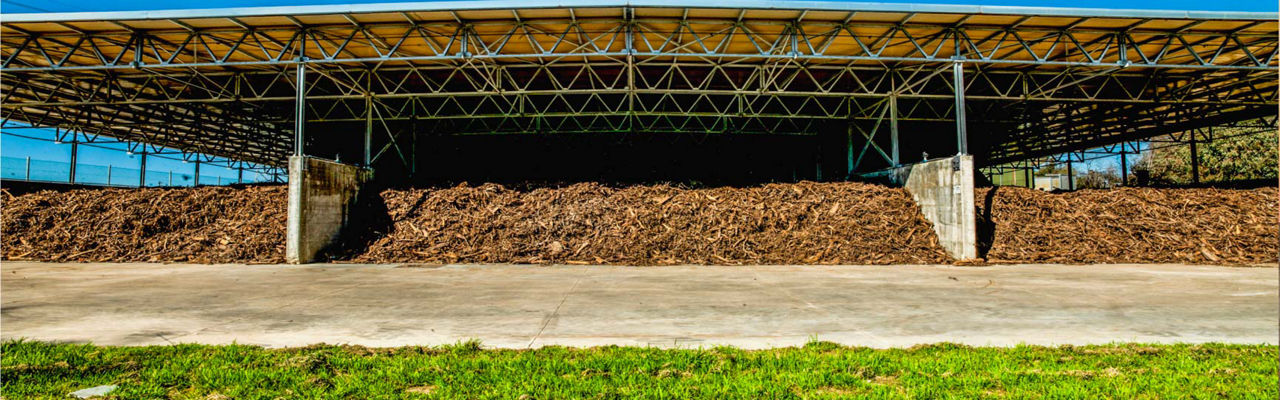 Area di stoccaggio all'aperto con cumuli di materiale organico, simbolo di gestione sostenibile dei rifiuti.