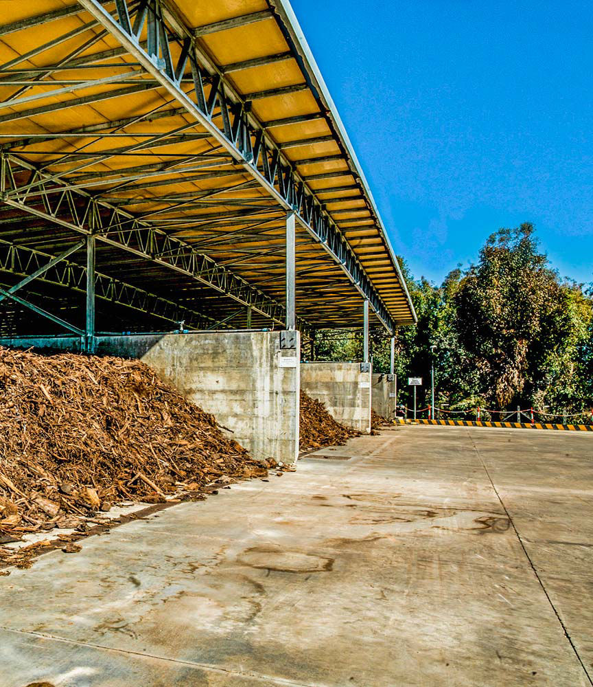 Area di stoccaggio all'aperto con cumuli di materiale organico, simbolo di gestione sostenibile dei rifiuti.