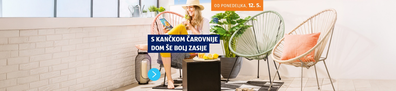 Nasmejana ženska na terasi sedi na stolu, pije limonado in gleda revijo