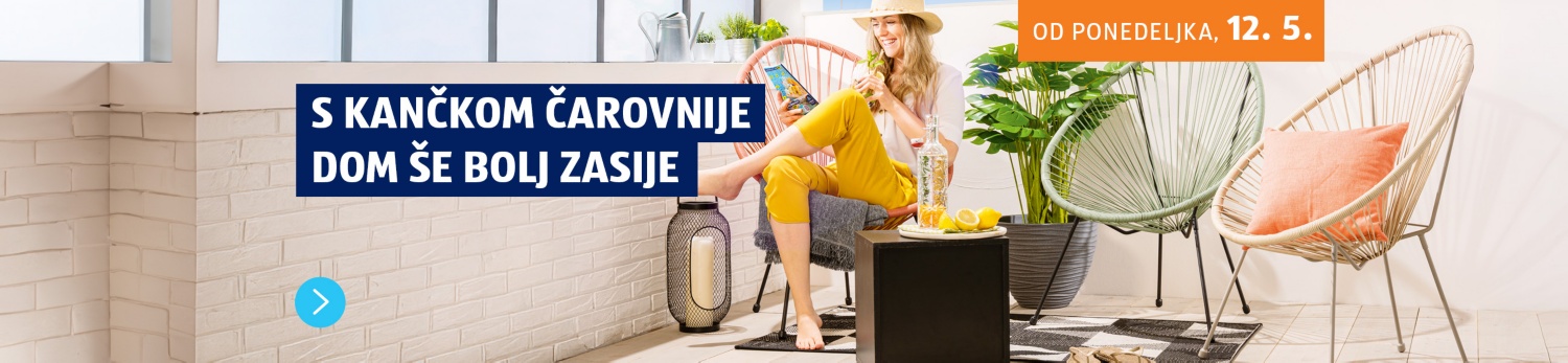 Nasmejana ženska na terasi sedi na stolu, pije limonado in gleda revijo