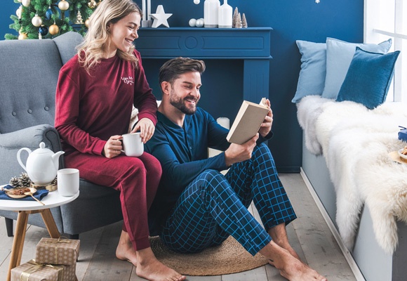 Moški in ženski v pižamah, moški ima v roki knjigo, ženska čaj