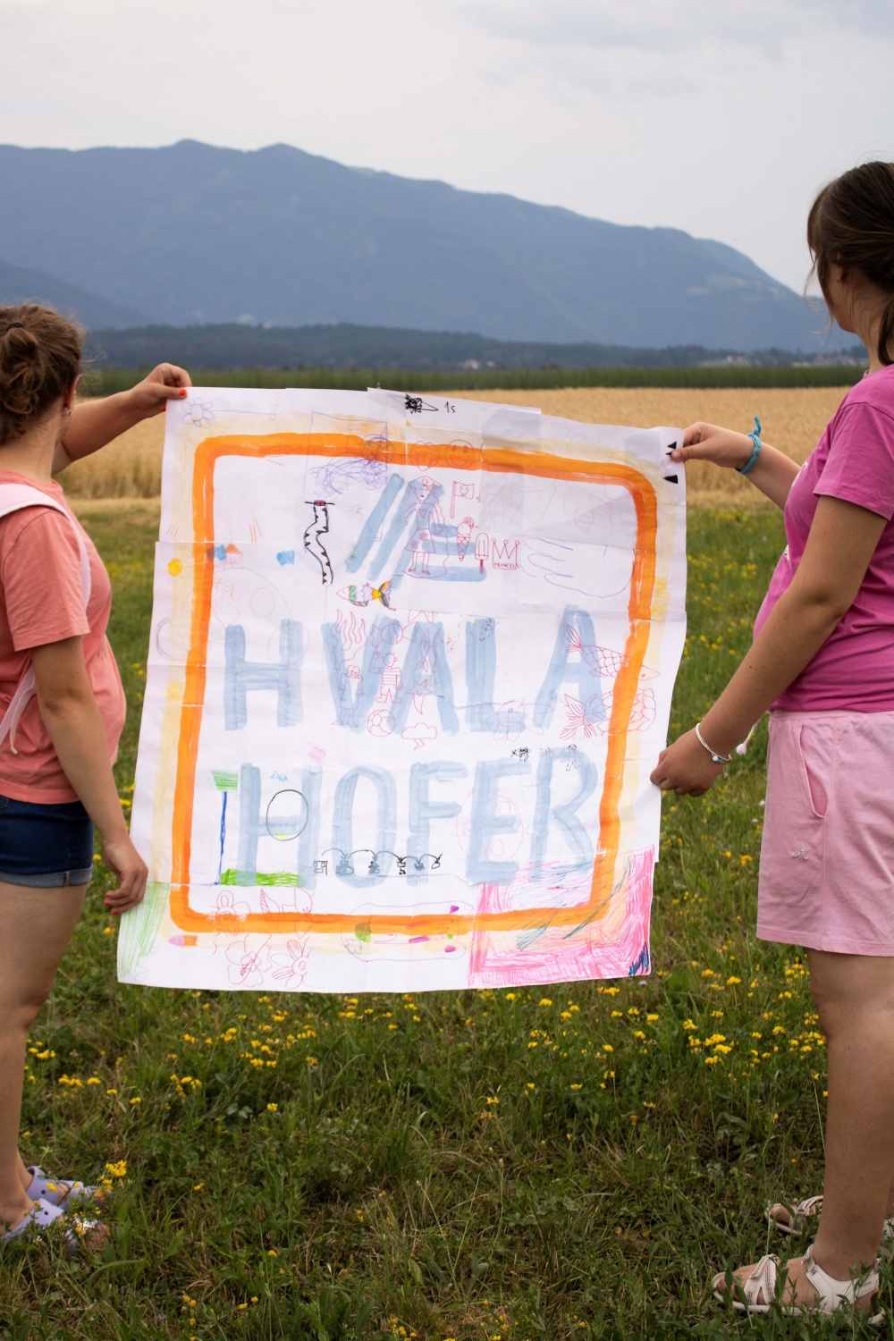 Dve punčki držita transparent z napisom HOFER hvala.