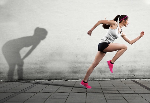 Eine Frau sprintet mit pinken Sportschuhen nach links, während ihr Schatten keuchend zurückbleibt.