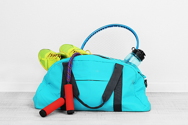 Türkise Sporttasche mit Laufschuhen, einer Trinkflasche und einem Springseil 