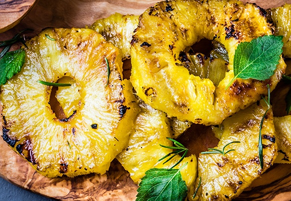 Mehrere gegrillte Ananas auf einem Holzbrett.