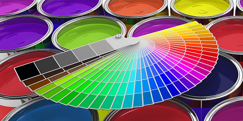 Viele unterschiedliche offene Farbdosen mit bunten Farben. Darauf liegt eine zu einem Fächer ausgebreitete Farbpalette.