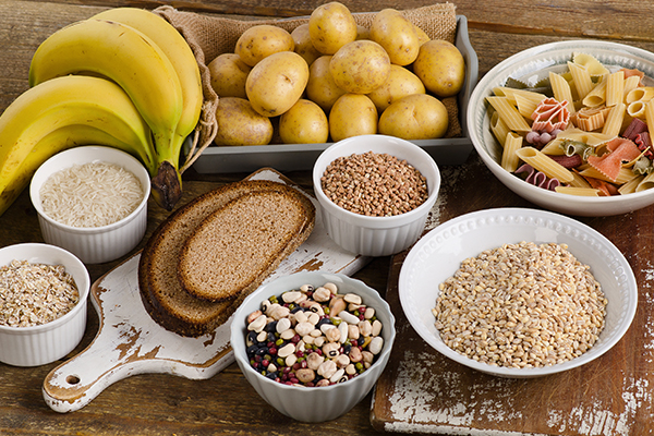 ananen, eine kleine Schachtel mit Kartoffeln, mehrere Schüsseln mit unterschiedlichen Getreidearten und eine Schüssel mit Pasta sind auf einem Holztisch zu sehen.