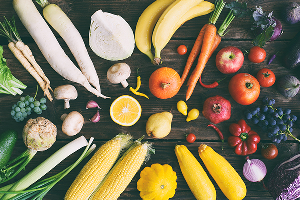 Unterschiedliche Obst- und Gemüsesorten liegen auf einem dunklen Holzuntergrund.