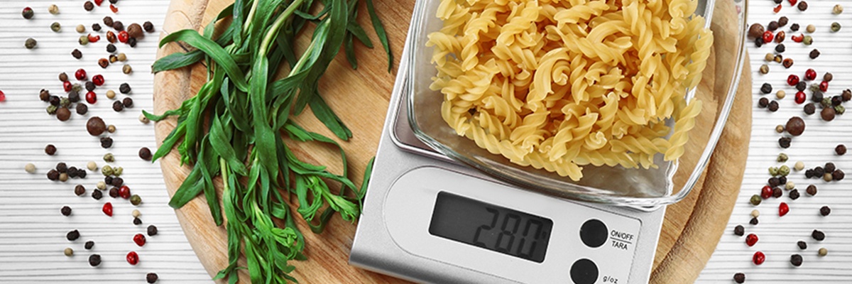 Eine elektrische Küchenwaage auf der gerade Spiralnudeln abgewogen werden.