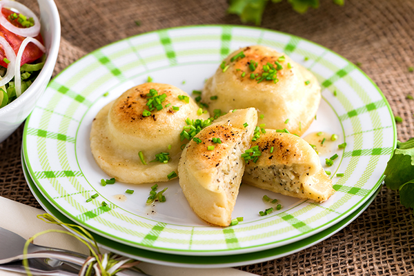 Kasnudeln auf einem grün-weißen Teller ganriert mit Schnittlauch.