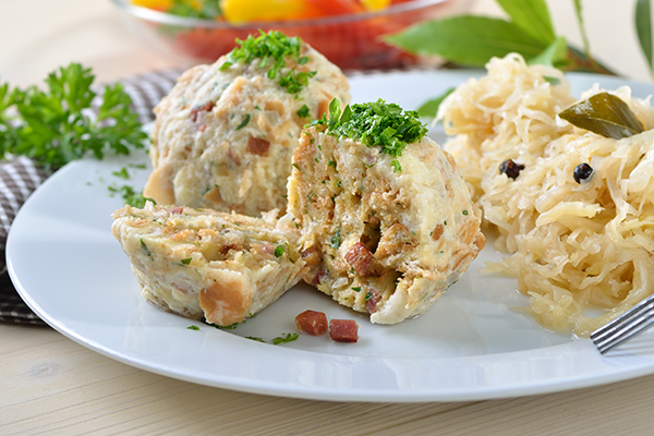 Tiroler Speckknödel mit Sauerkraut, garniert mit Schnittlauch.
