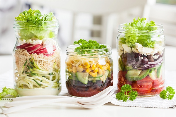 Drei gemischte bunte Salate in Einmachgläser.