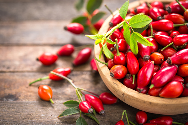 Eine Holzschale voll mit roten Hagebutten.