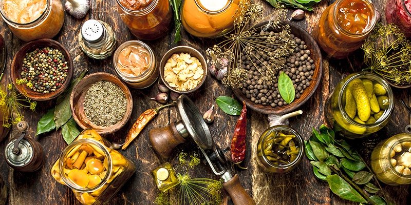 Schüsseln und Gläser gefüllt mit Gurken, Bohnen, Obst und bunten Gewürzen.