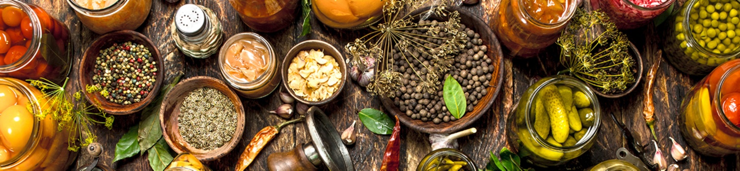 Schüsseln und Gläser gefüllt mit Gurken, Bohnen, Obst und bunten Gewürzen.