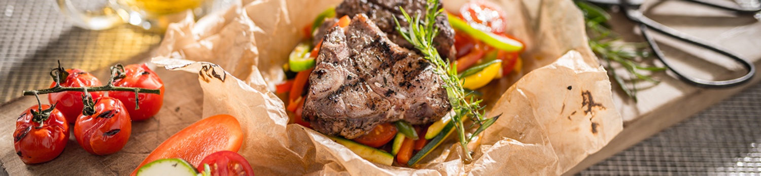 Saftig-zartes Fleisch liegt auf buntem Gemüse und wurde mediterran zubereitet.