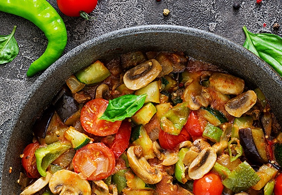 Eine bunte Gemüsepfanne mit Tomaten, Zucchini und Pilzen.