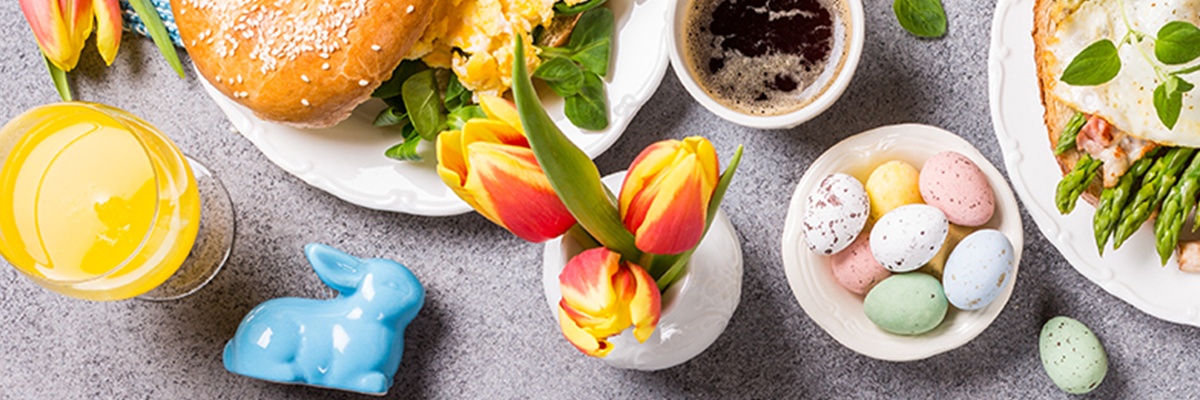 Blumen, Osterhasen, süßes Gebäck auf frühlingshaftem Untergrund. 