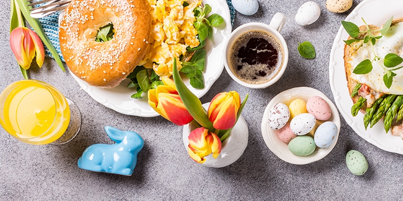 Ein österlich gedeckter Tisch mit Spiegelei, Tulpen und Hasenfigur.