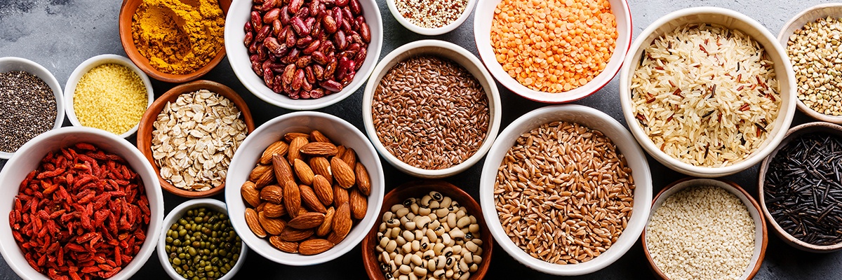 Viele Schüsseln voller Superfoods wie Nüsse, Reis und Haferflocken.