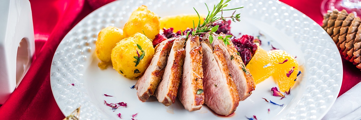 Ein zarter Braten liegt aufgeschnitten neben Kartoffeln und Rotkraut.