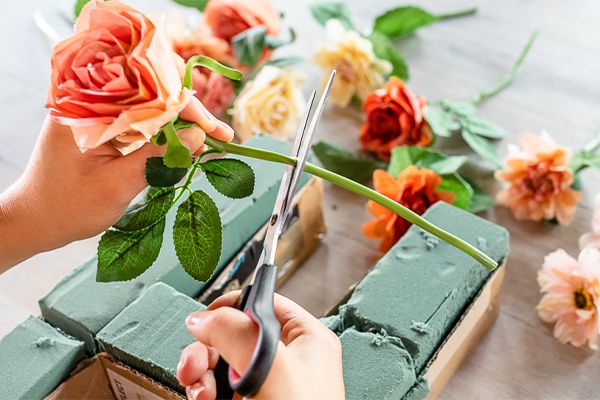 Blumen für einen Papierschriftzug in Steckschwämmen platzieren