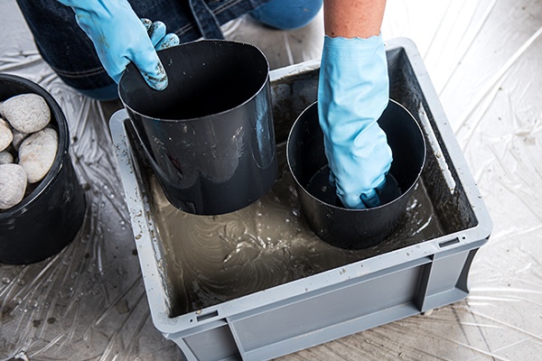 Beton für die DIY-Pflanzentöpfe in Form gießen und zwei Behälter darin versenken