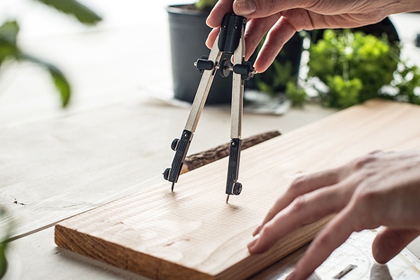 Mit einem Zirkel Kreise auf das Holzen vorzeichnen
